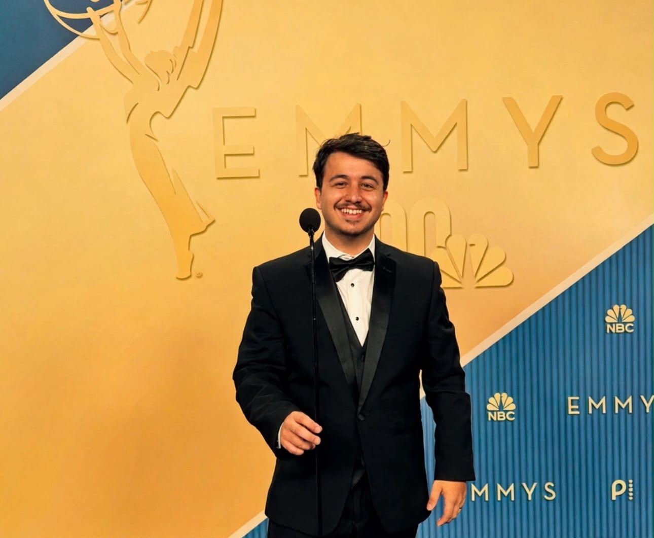 Victor Luzzi in a tuxedo, photographed against the Emmy Awards backdrop